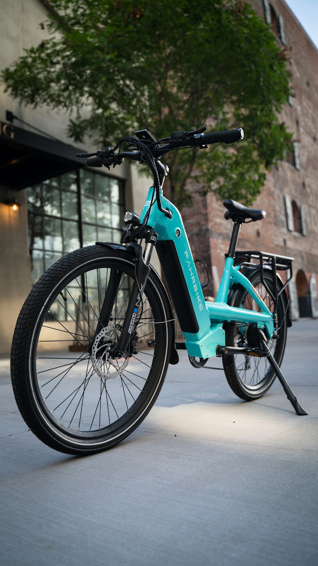 a-black-bicycle-parked-in-front-of-a-gate-and-a-tree-qqzx7eokcum